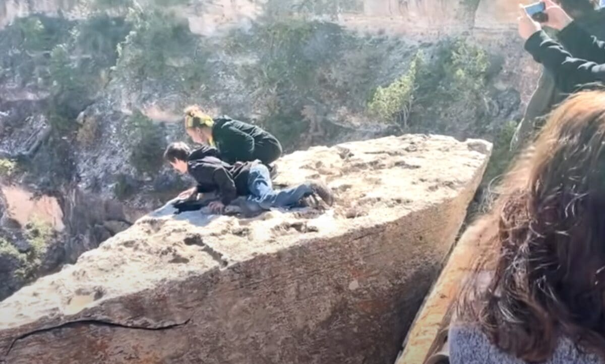 Tourists hop protective railing at Grand Canyon National Park.